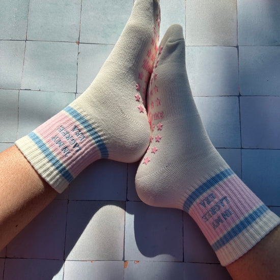 Cream pilates non slip grip sock with pink and blue stripes and pink star grips.  "in my lagree era" is embroidered on them. Used for Pilates, yoga, lagree and barre